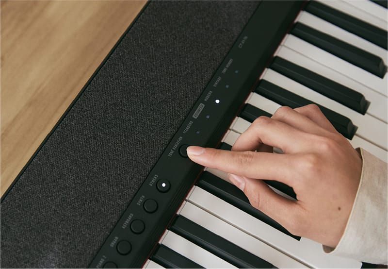 Nahaufnahme auf Tastatur und Bedienfeld eines  schwarzen Casiotone CT-S1-76, ein Finger drückt einen Knopf des Bedienfeldes
