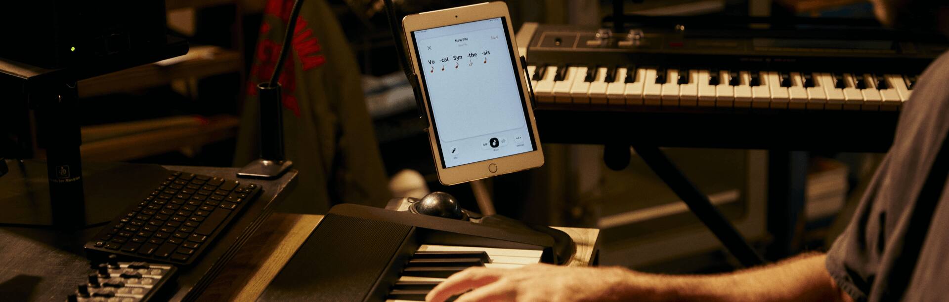 Eine Person sitzt am Casio Keyboard, rechts daneben die Lyric Creater App auf einem Tablet.