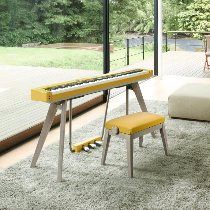 Das senfgelbe PX-S7000 steht mit passendem Hocker auf einem Teppich.