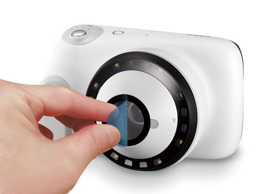 Eine Hand zieht die Schutzfolie von der Kameralinse