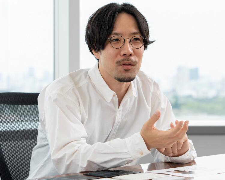 Shunsuke Oka, Design Department, mit Brille und weißem Hemd an seinem Schreibtisch