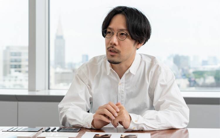 Shunsuke Oka, Design Department, mit Brille und weißem Hemd an seinem Schreibtisch