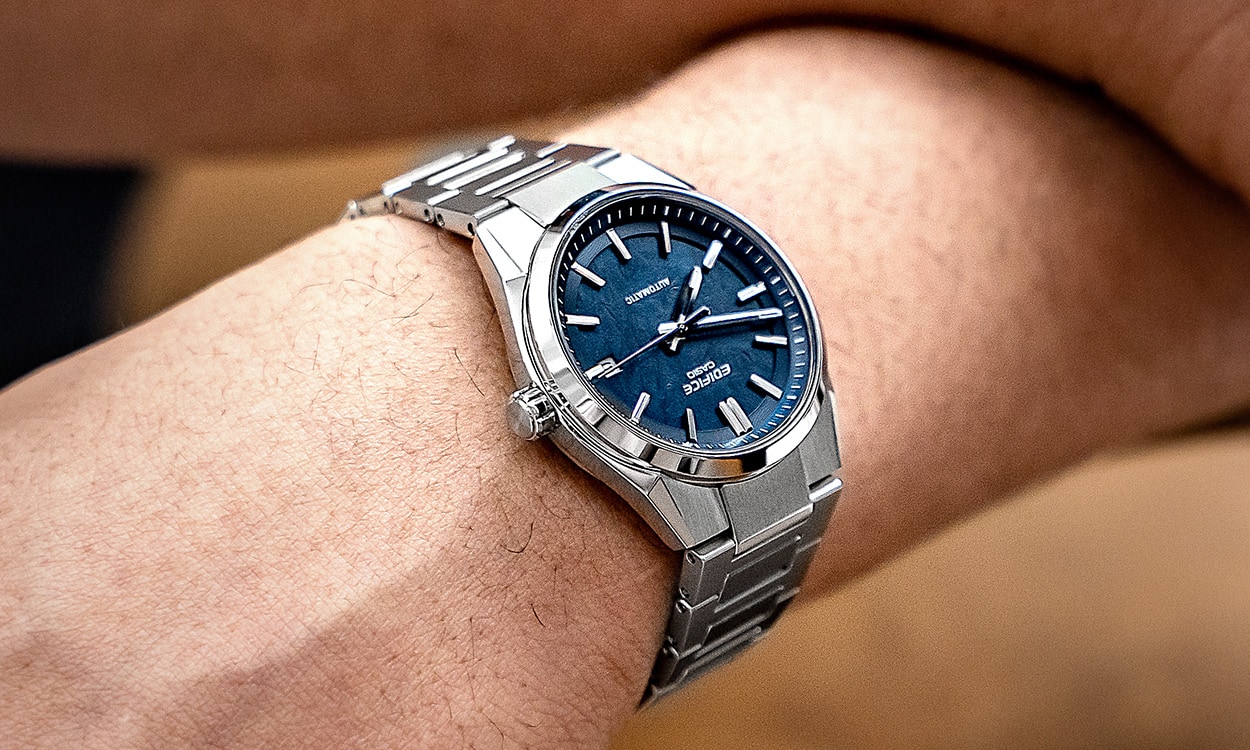Nahaufnahme auf das Handgelenk eines Mannes, der die silberne EFK-110 Automatik-Uhr am Handgelenk trägt mit blauem, analogem Zifferblatt.