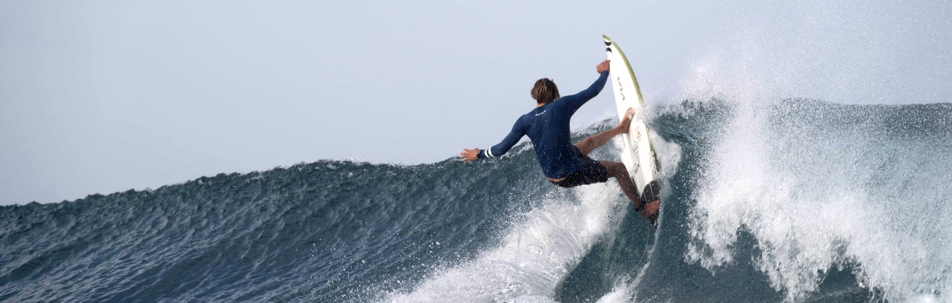 Ein Surfer auf hoher Welle mit der G-Shock G-Lide Armbanduhr am Handgelenk. Das Bild verlinkt zur G-Shock-Produktübersicht mit G-Lide-Filter. 