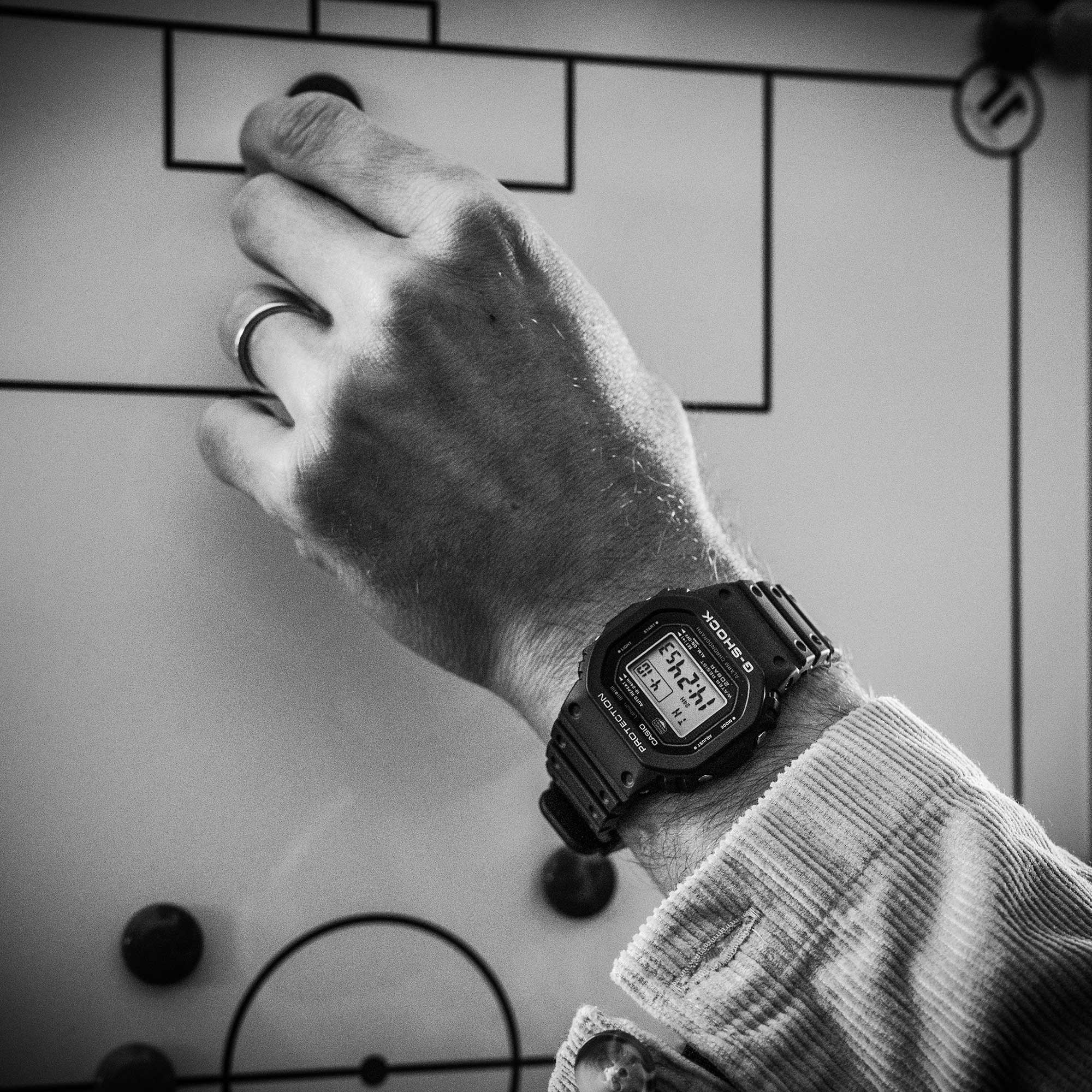 Nahaufnahme auf das Handgelenk von Sandro Wagner bei der Planung der Spieleraufstellung. Am Handgelenk trägt er die DW-5000R-1A Armbanduhr mit schwarzem Resinband und rechteckiger, digitaler Anzeige.