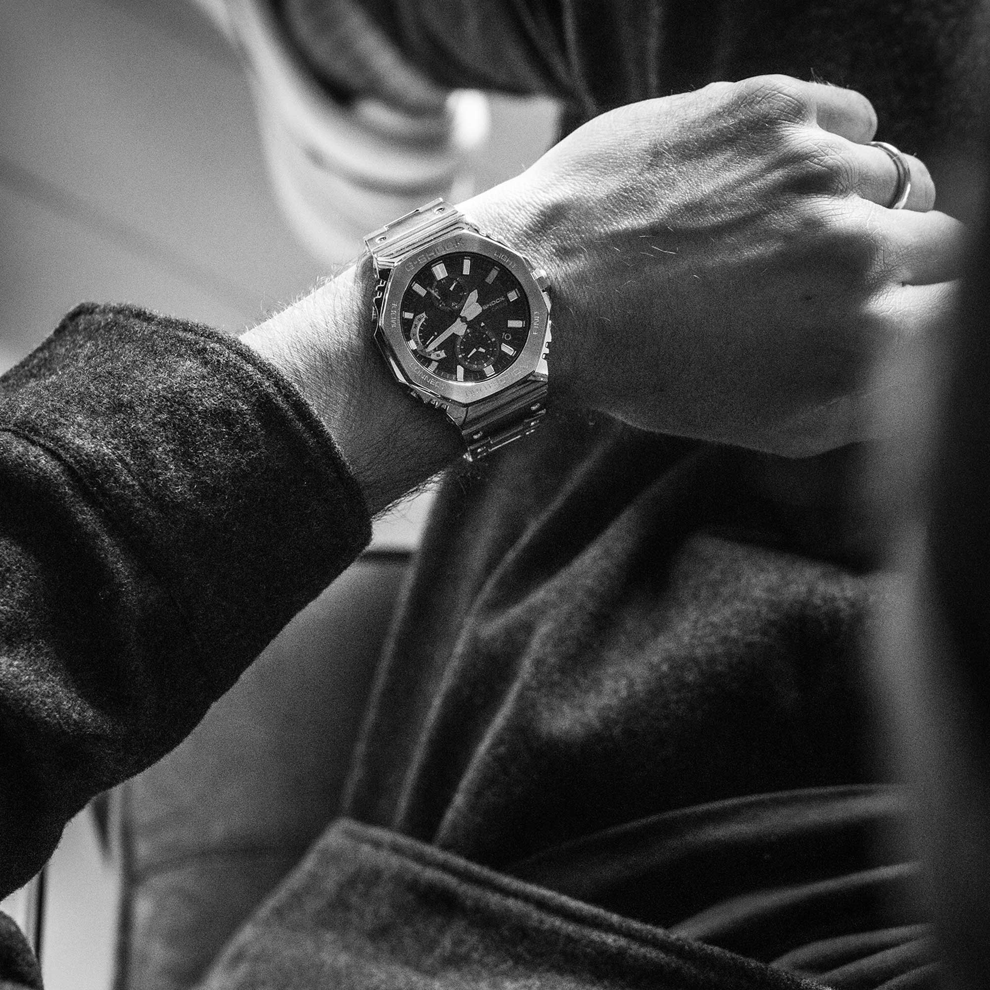 Vogelperspektive auf das Handgelenk von Sandro Wagner, daran trägt er dien Chronographen GMC-B2100D-1A mit silbernem Band und Gehäuse und dunklem Zifferblatt.