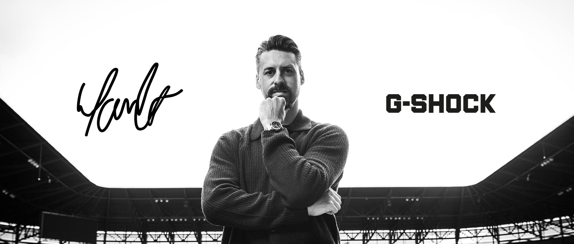 Schwarz-weiß Portrait von Sandro Wagner, der im Stadion vorm Fußballfeld steht, am Handgelenk trägt er eine Metal-Uhr von G-SHOCK.