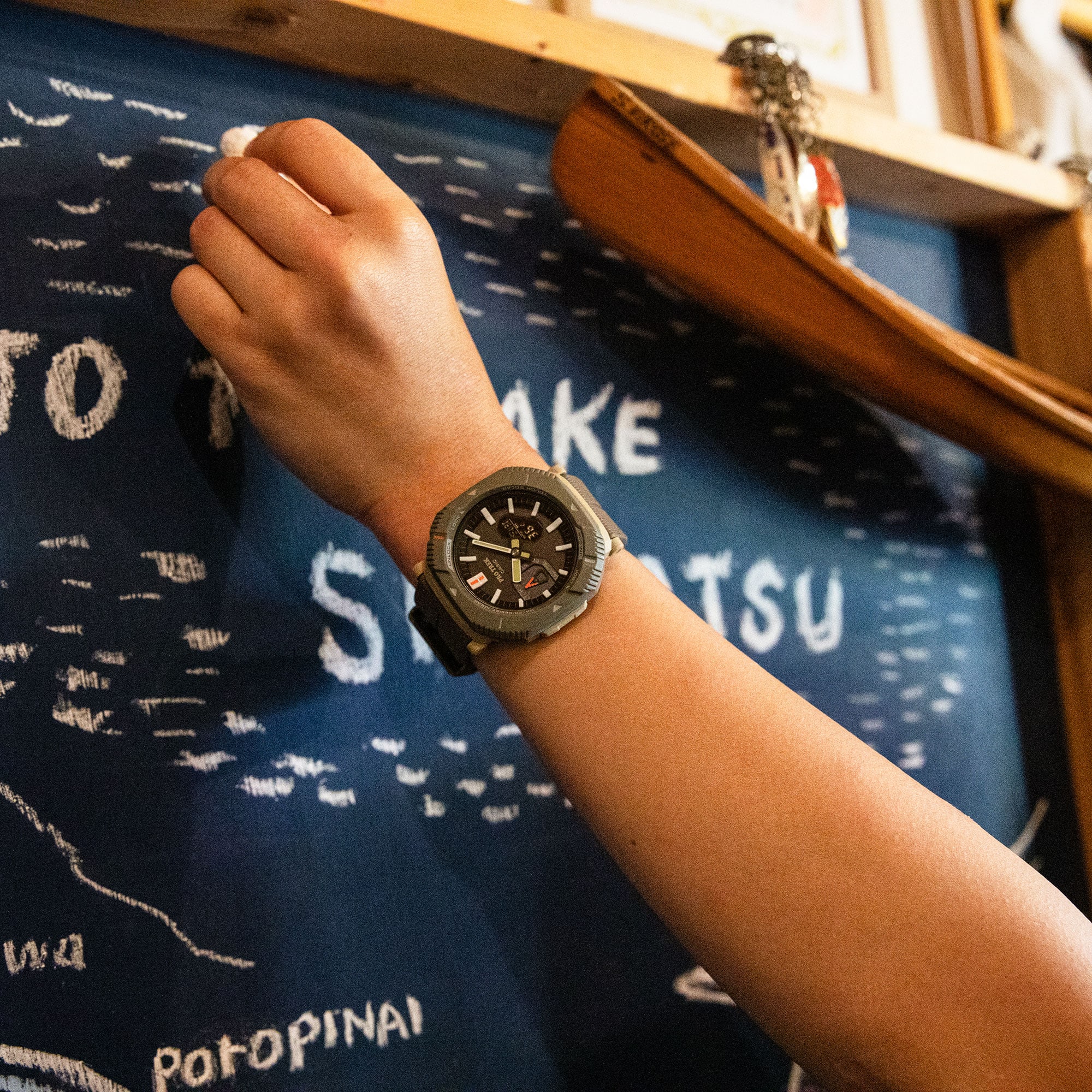 Die anthrazit-farbene Pro Trek PRJ-B001-1 Armbanduhr am Handgelenk einer Person, die mit Kreide auf eine Wandtafel schreibt