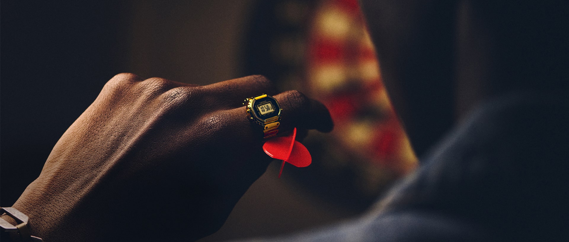 Gold CRW001G-9 Casio ring watch on a person's finger while they throw a dart denoting style and size.