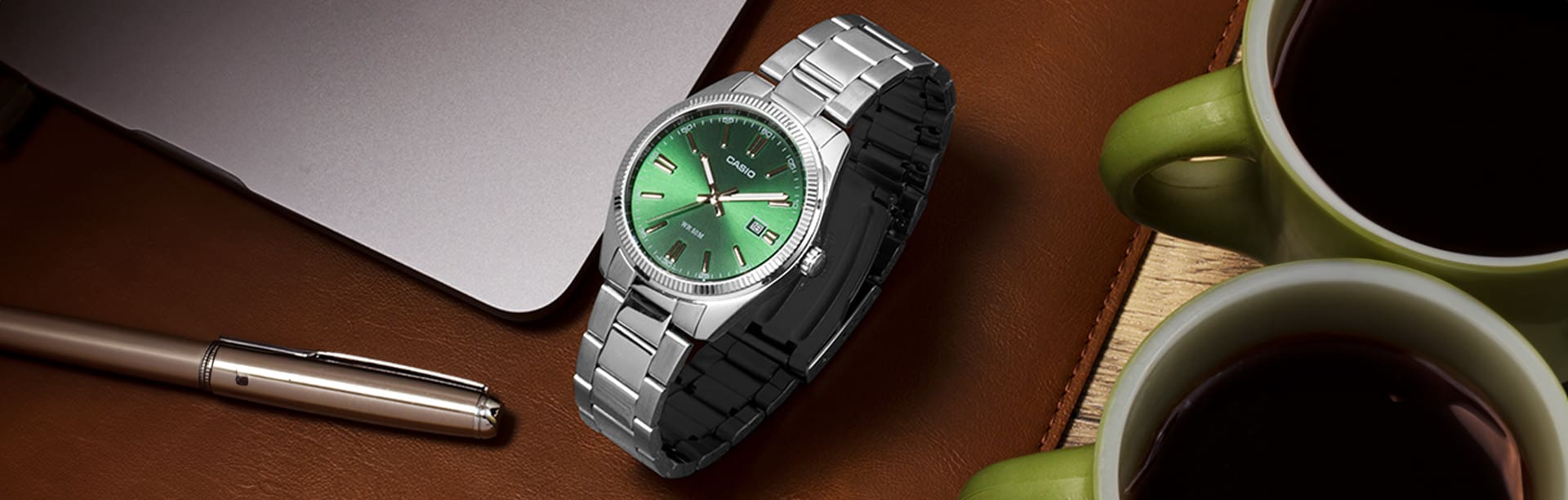 Minimalist watch CASIO model MTP1302D-3AVT in silver with green face on a desk.