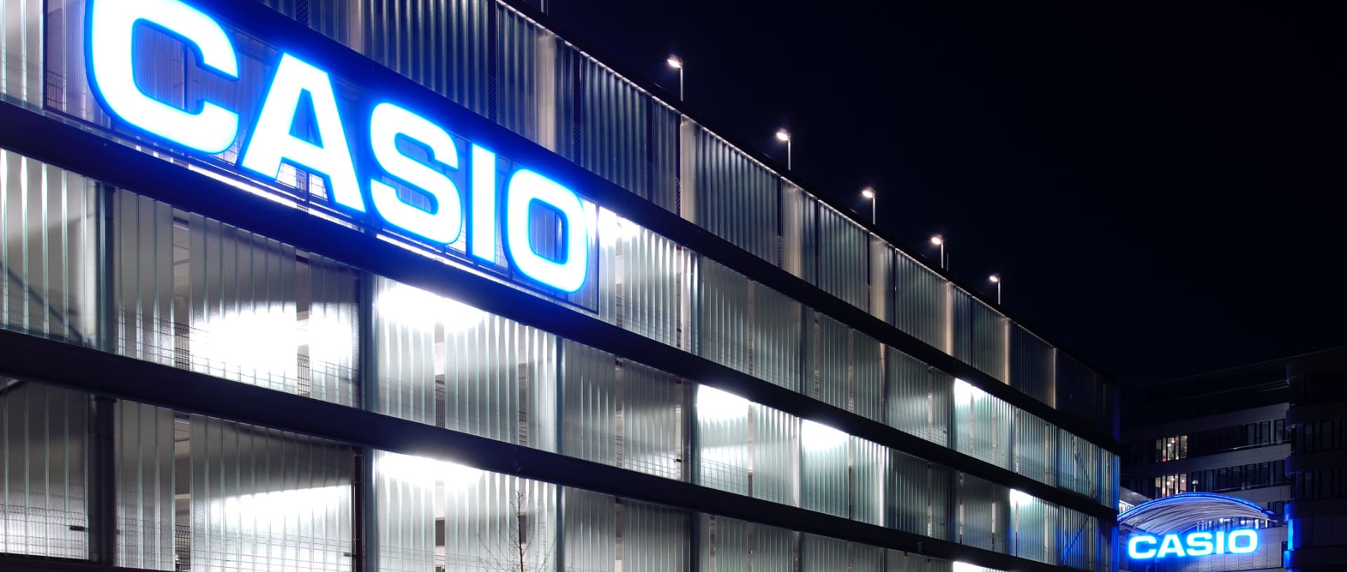 Das CASIO Office in Norderstedt bei Nacht mit dem blau-beleuchtetem Schriftzug am Haupteingang und am Parkhaus