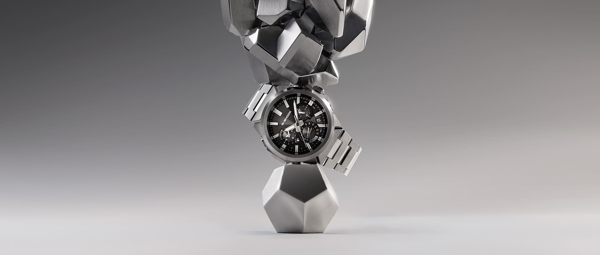 Der silberne G-Shock G-Steel Chronograf GST-W1000 zwischen zwei silbernen Metallbrocken liegend