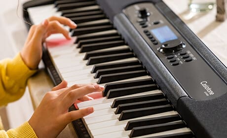 Klavierspielende Kinderhände über den Tasten des Casiotone LK-S450 Digitalpiano von Casio.