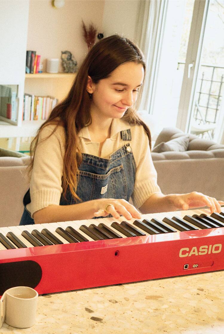 Café-Besitzerin Margaux Salgado spielt in ihrer Pariser Wohnung auf ihrem roten Privia. Das Bild verlinkt zu ihrer Life with Privia-Seite.
