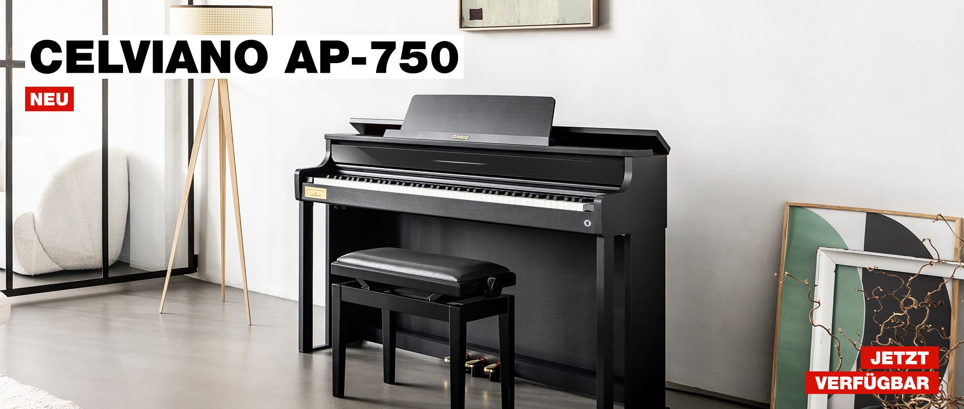 Das schwarze CELVIANO Digitalpiano mit einem schwarzen Hocker vor einer weißen Wand, daneben steht eine Stehlampe und grün-schwarze Gemälde