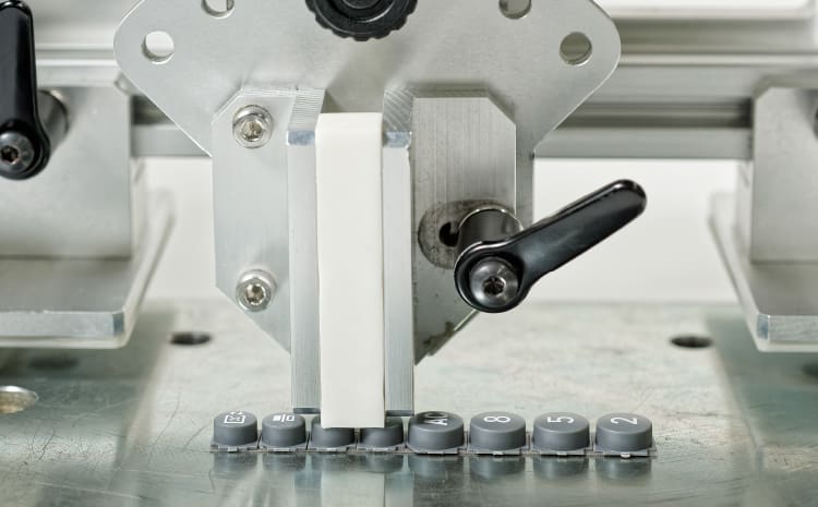 Einzelne Tasten der CASIO Grafikrechner werden in einer Maschine auf Verschleiß geprüft.