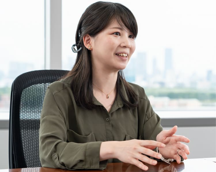 Miki Suzuki, Hardware Strategy Abteilung, sitzt in brauner Bluse vor ihrem Schreibtisch