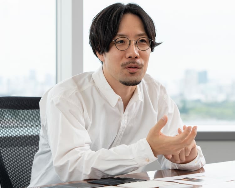 Shunsuke Oka, Design Department, mit Brille und weißem Hemd an seinem Schreibtisch