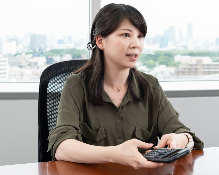 Miki Suzuki, Mitarbeiterin von CASIO, mit einem wissenschaftlichen Rechner in ihrer Hand am Schreibtisch