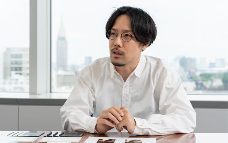 Shunsuke Oka, Design Department, mit Brille und weißem Hemd an seinem Schreibtisch