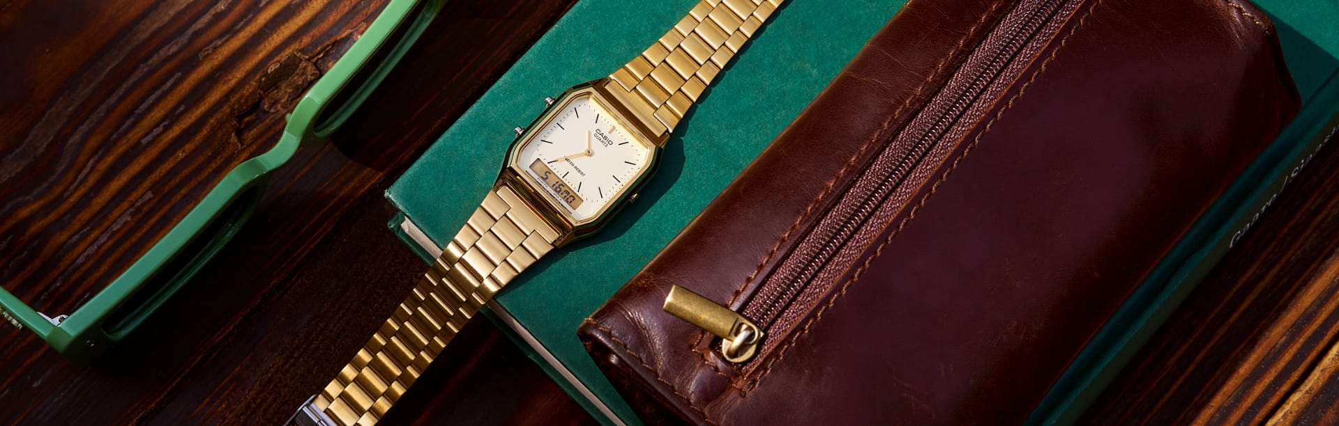 Die CASIO Vintage Uhr AQ-230GA-9DMQYES von oben, auf einem grünen Notizbuch neben einem Portemonnaie und einer Sonnenbrille