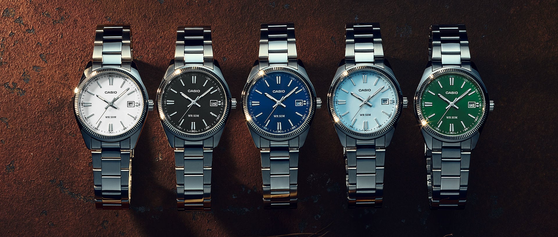 Fünf CASIO Armbanduhren UTP-1302PD aus dem CASIO TIMELESS COLLECTION mit verschiedenfarbigen Zifferblättern auf dunklem Hintergrund. Das Bild verlinkt zur Produktseite.