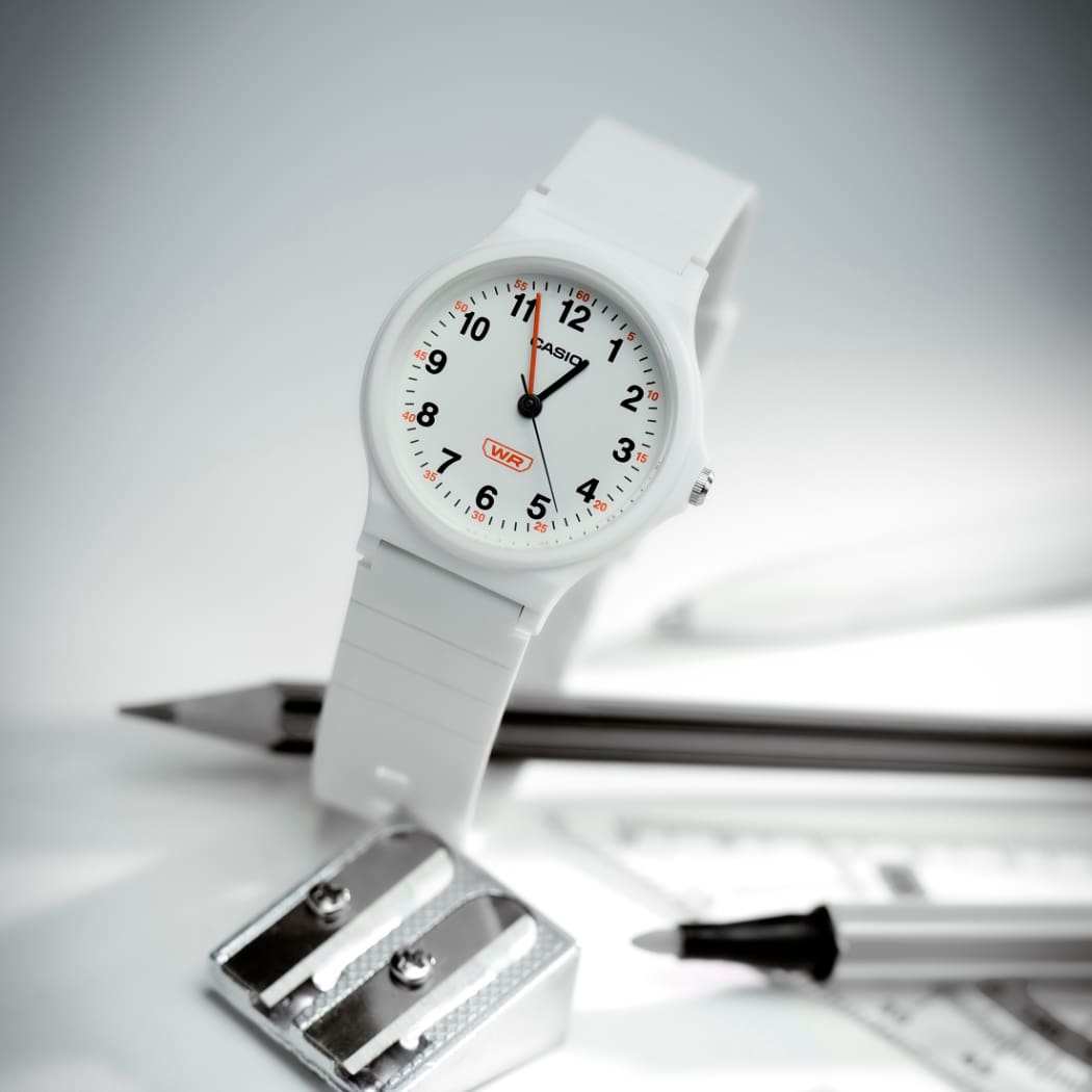 Die weiße CASIO TIMELESS COLLECTION Uhr LQ-24B ist auf einem Tisch neben Bleistift, Anspitzer und Filzstift platziert.