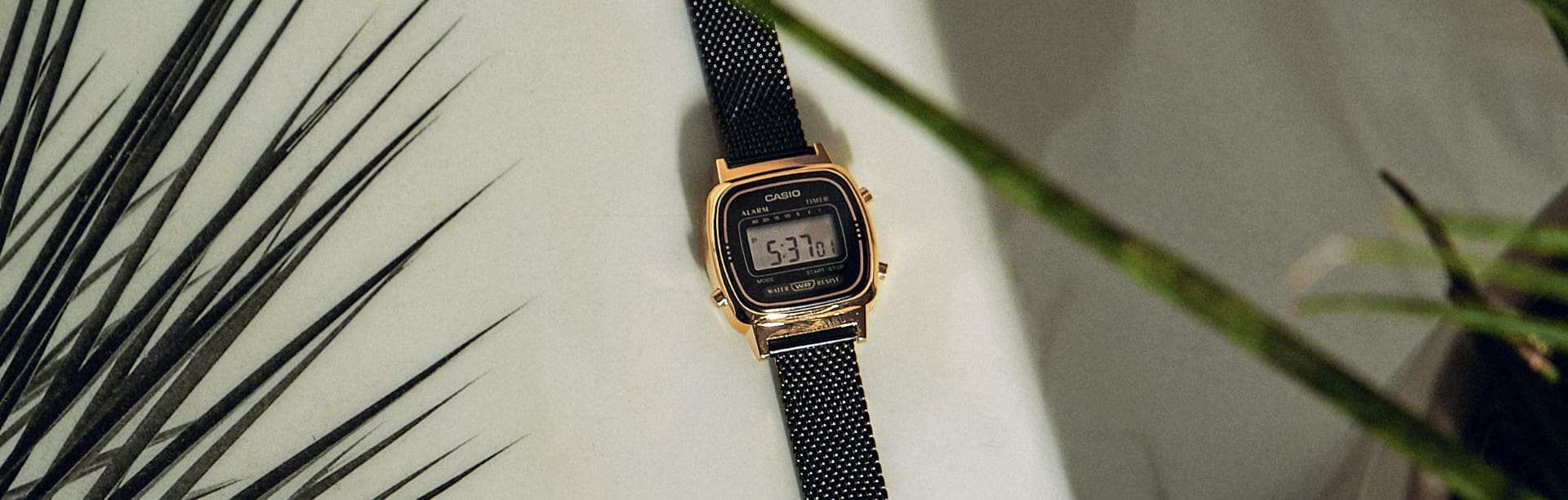 Die kleinere Uhr LA-680 aus der Casio Vintage Collection mit goldenem Gehäuse und kleiner schwarzer Digitalanzeige auf einem weißen Tisch.