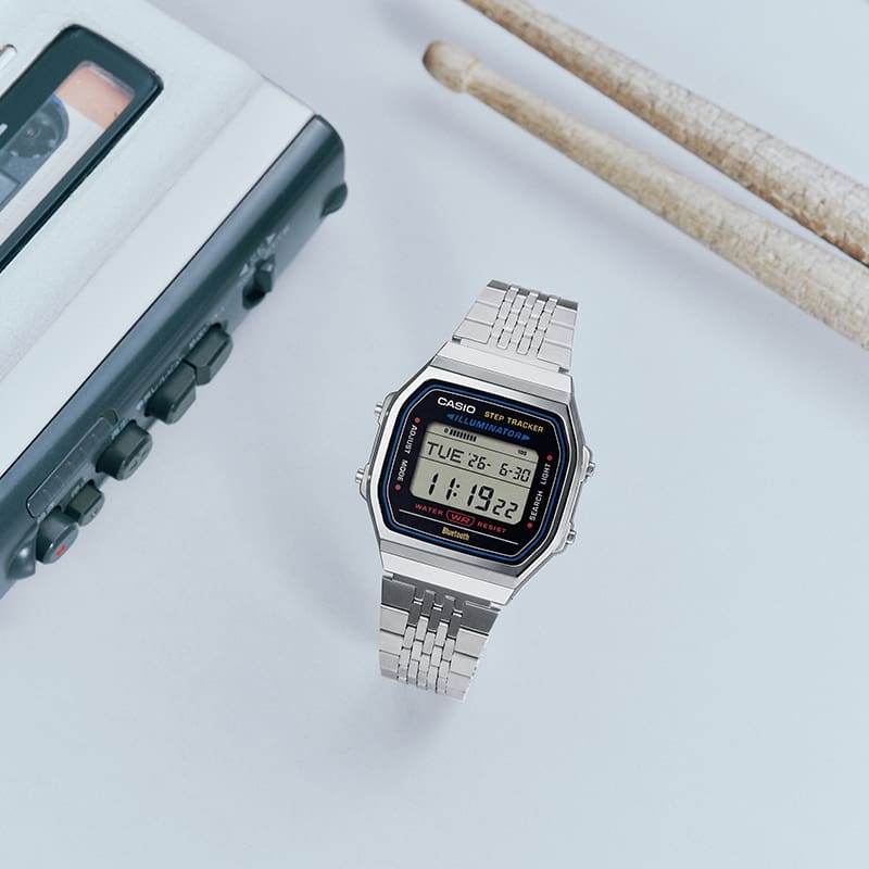 Die Uhr ABL-100WE-1A mit Schlagzeugstöcken und Audiogeräten platziert.