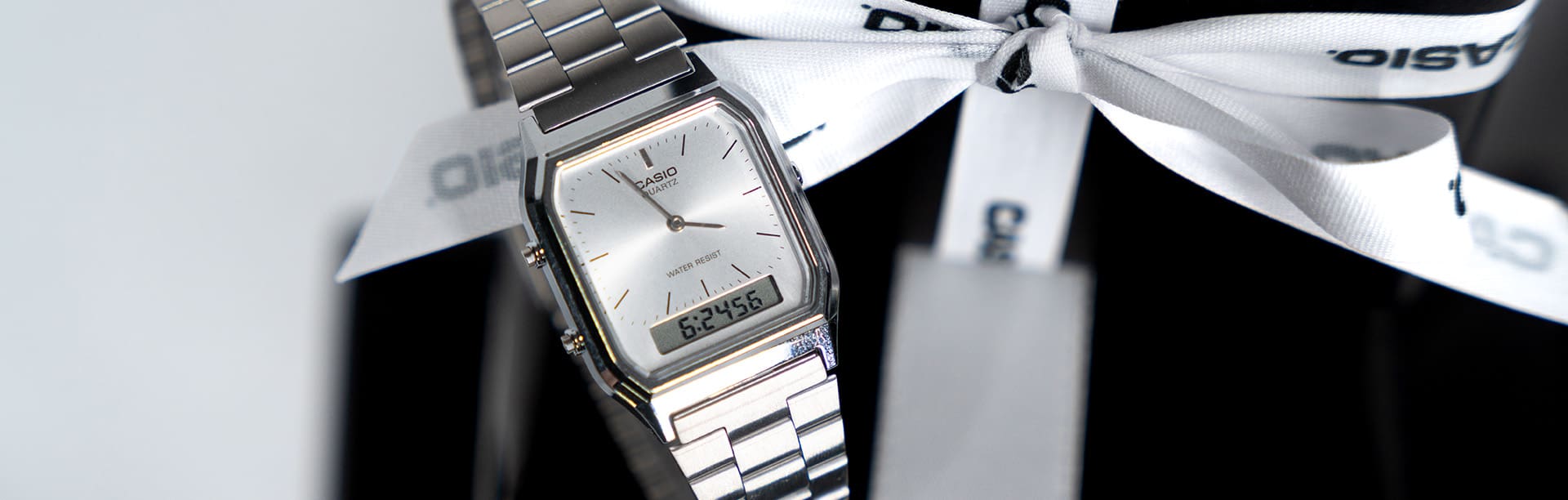 Die silberne, analoge Casio Vintage Collection Uhr AQ-230A-7DMQ auf einem Stapel von Weihnachtsgeschenken