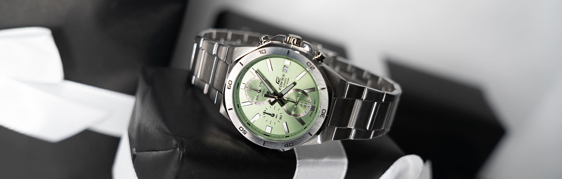 Die silberne Analoguhr EFV-640D-3AV mit hellgrünem Zifferblattauf einer schwarzen Geschenkverpackung.