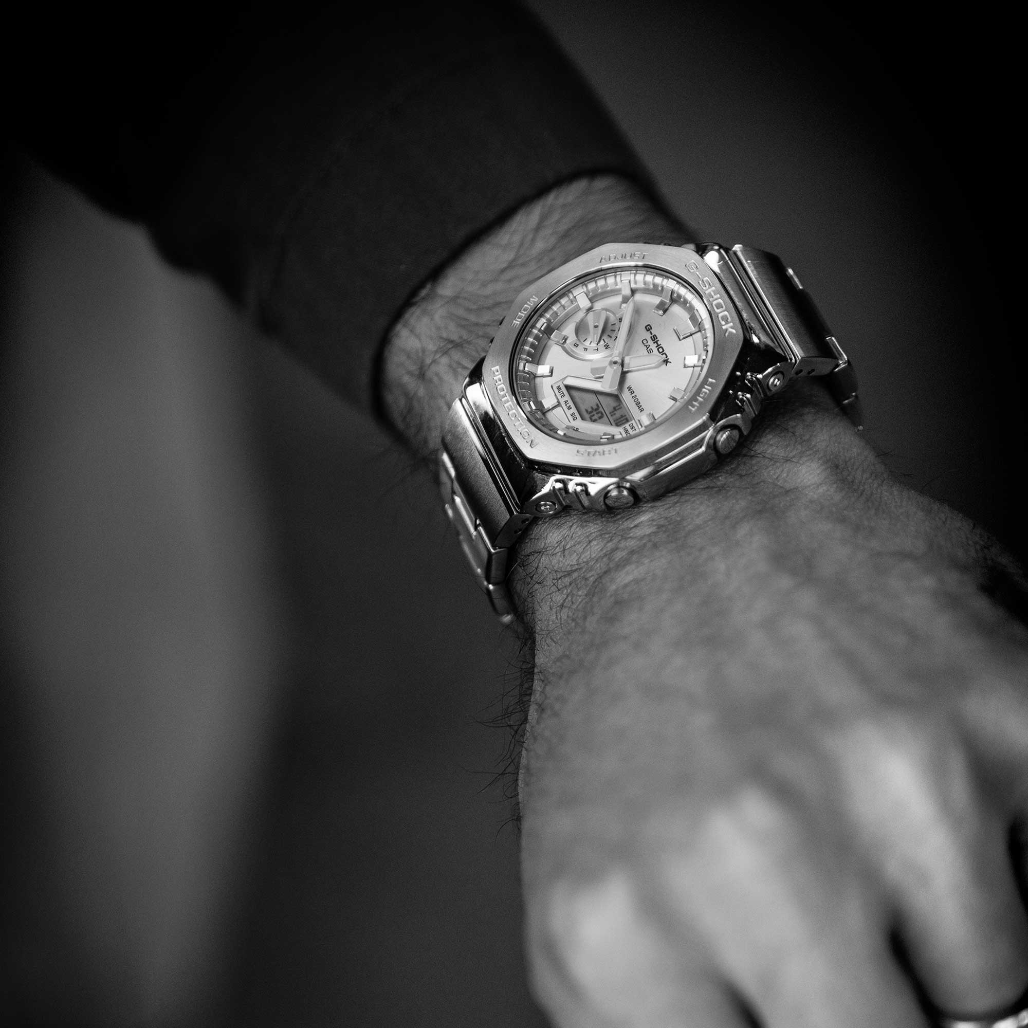 Nahaufnahme auf ein Handgelenk, an dem die GM-2110D-2A Armbanduhr getragen wird. Die Uhr hat ein silberfarbenes Armband und Gehäuse und eine hellblaue, analoge Anzeige.