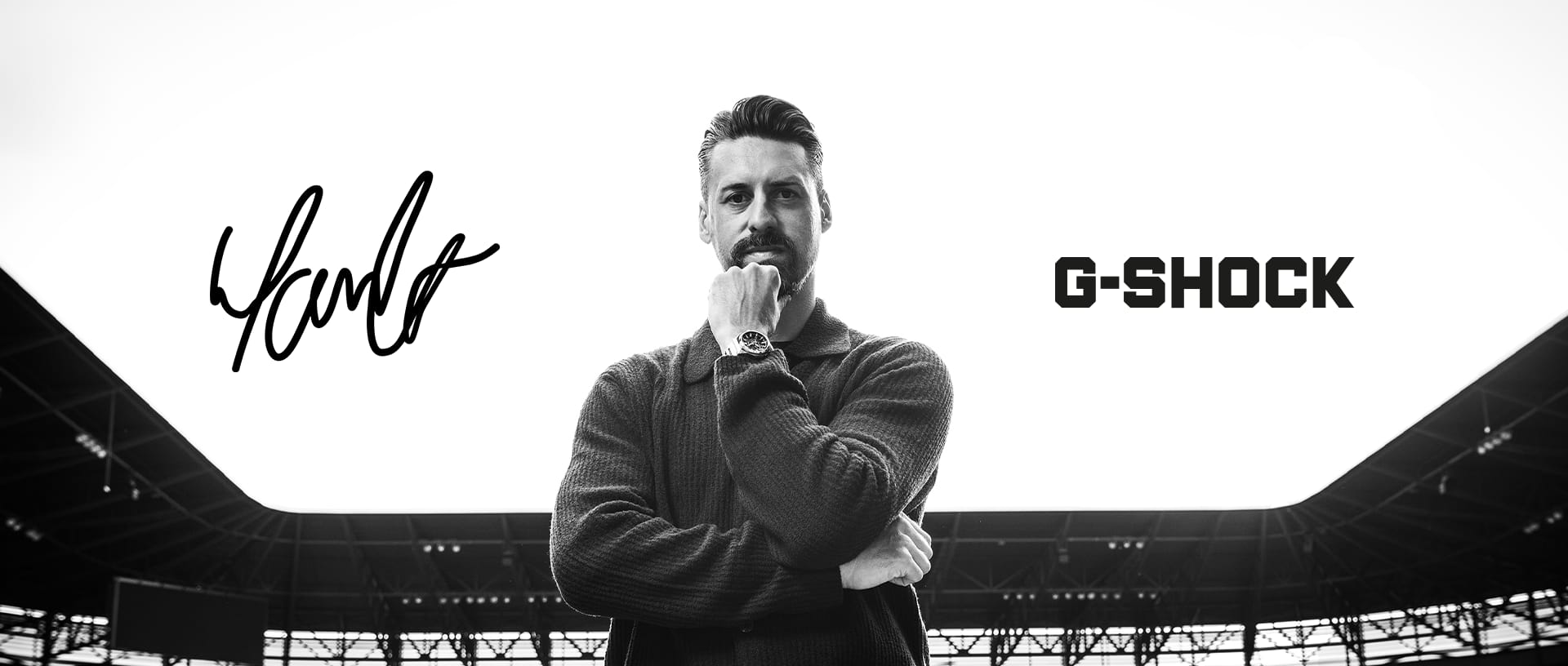 Schwarz-weiß Portrait von Sandro Wagner, der im Stadion vorm Fußballfeld steht, am Handgelenk trägt er eine Metal-Uhr von G-SHOCK.