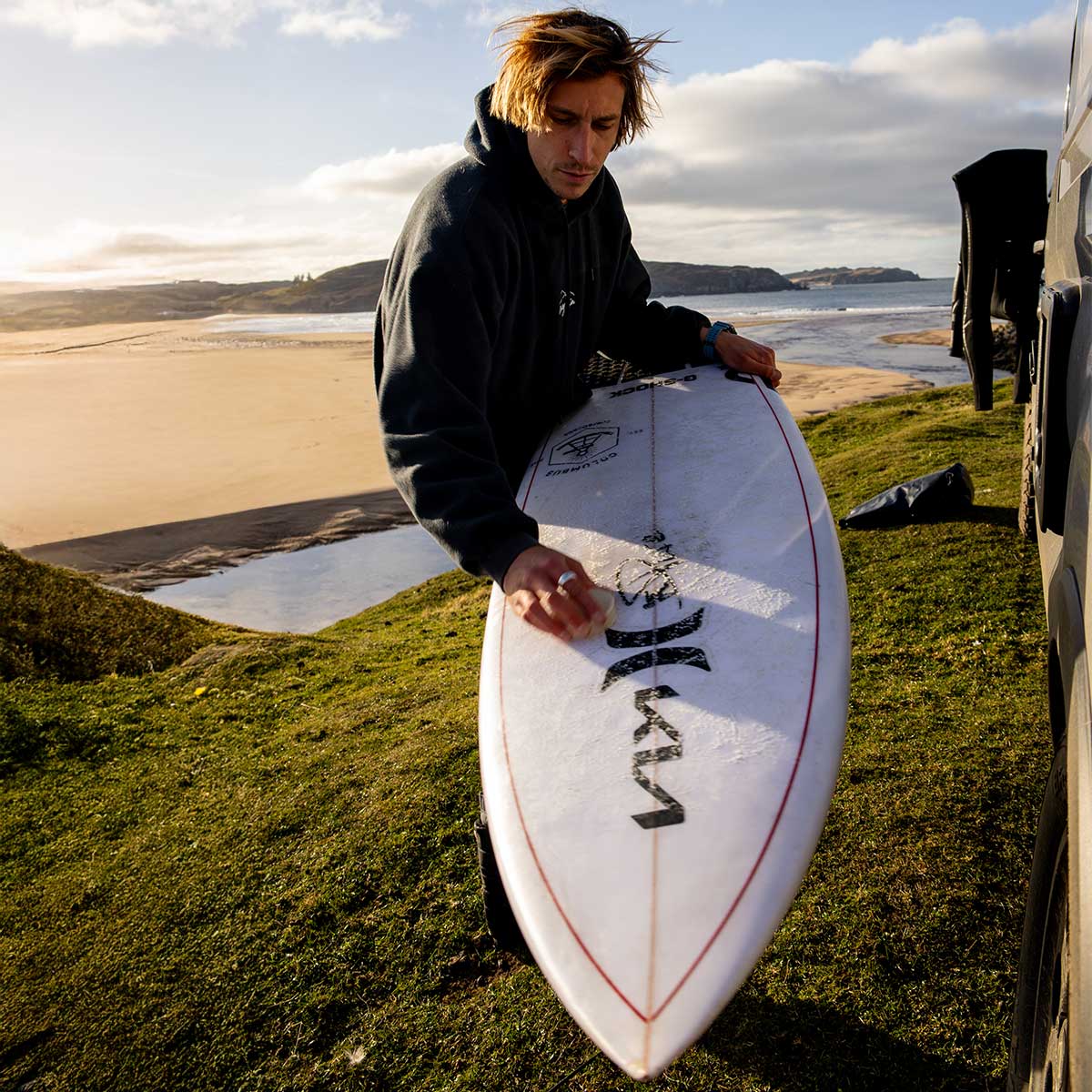 Finn Sprinborn wachst sein Surfboard an der Küste Schottlands.