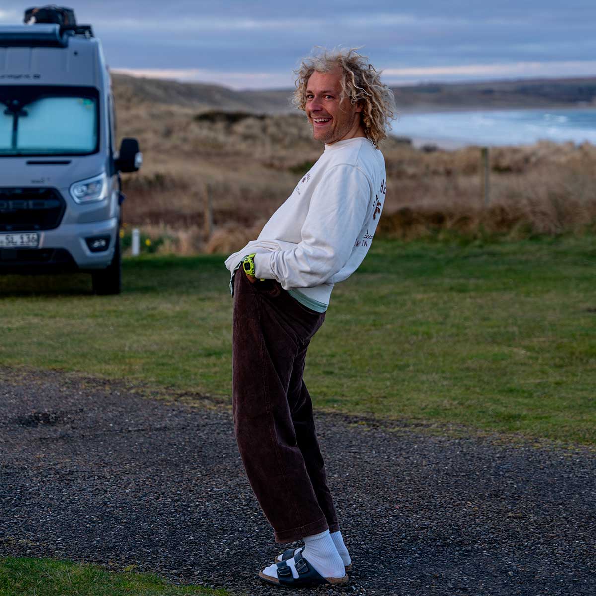 Jonathan Isselstein lacht draußen vor einem Campervan.