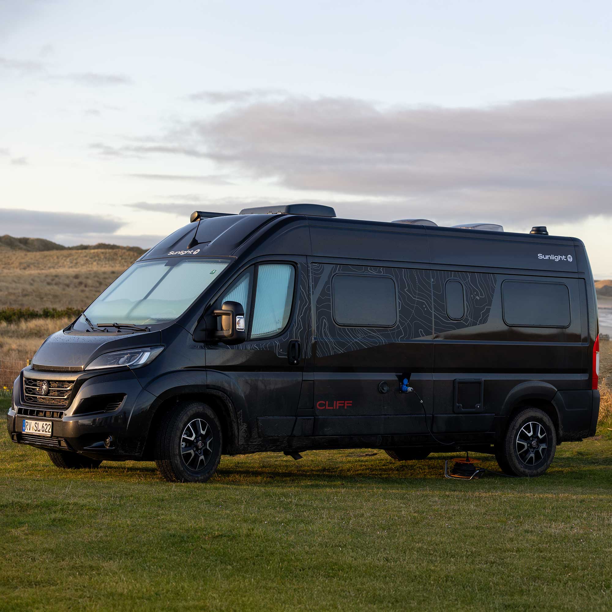 Der schwarze Cliff 600 Adventure Camper-Van auf einer grünen Wiese