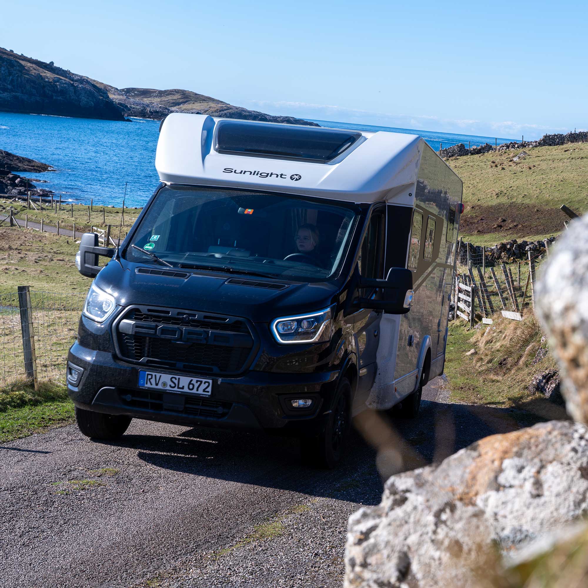 Der schwarze Sunlight T670 S Adventure -Van auf einem Weg an einem See.