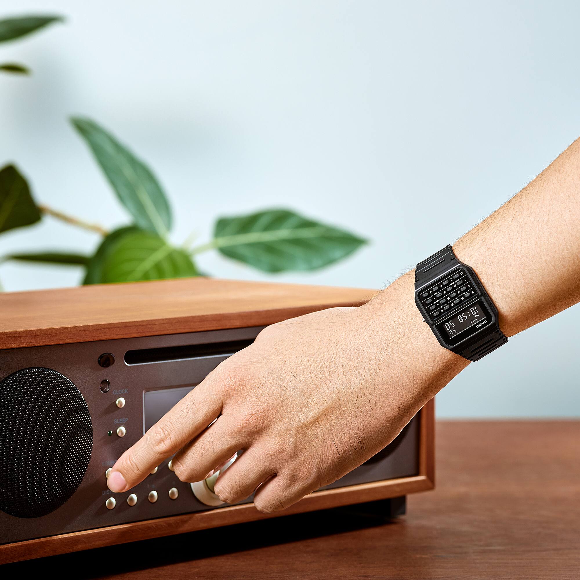 Am Handgelenk einer Person, die Knöpfe am Radio bedient, ist die Taschenrechneruhr "CA-53WF-1B" von CASIO Vintage in schwarz.