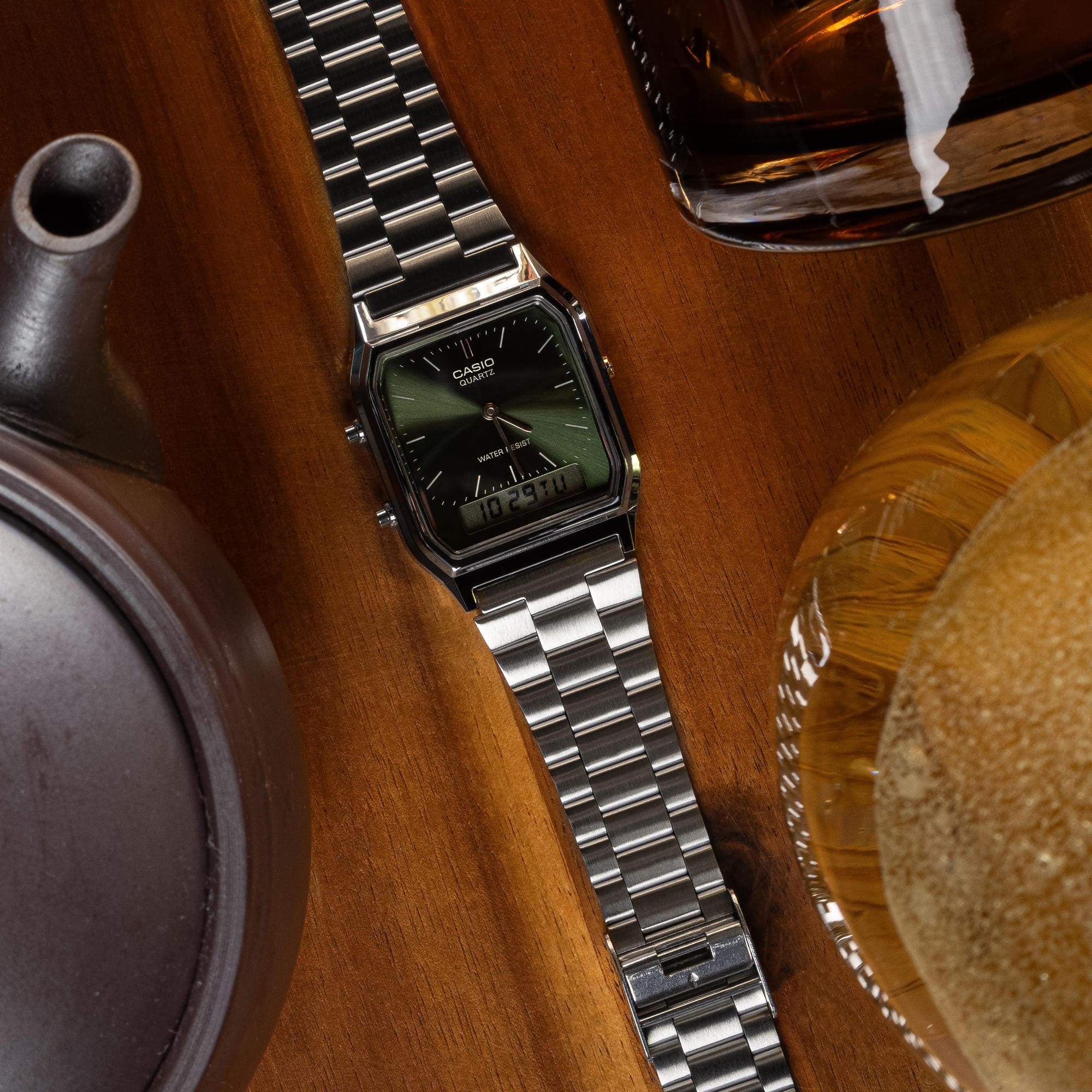 Die AQ-230A-3AMQY Hybrid-Armbanduhr mit silberfarbenem Armband und grünem Zifferblatt aus der Edgy Collection liegt auf einem Holztisch