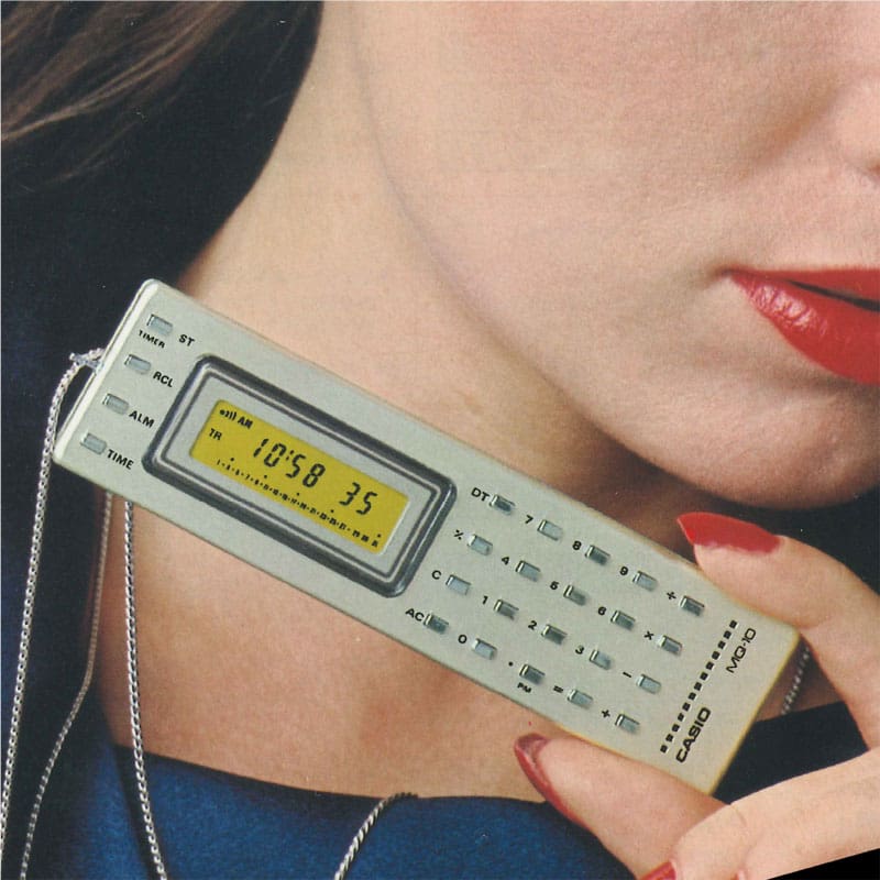 Una mujer muestra a la cámara con una fina cadena alrededor del cuello la calculadora CASIO MQ-1 gris y delgada, con una pantalla estrecha en el lado izquierdo y teclas numéricas pequeñas en el lado derecho.