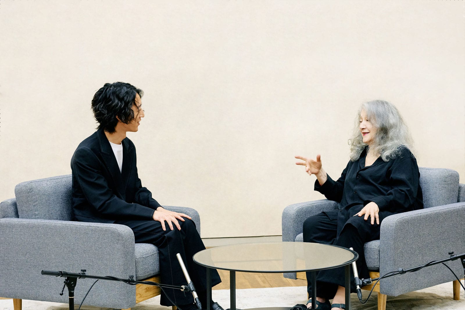 Argerich y Sumino conversando en sillones grises.