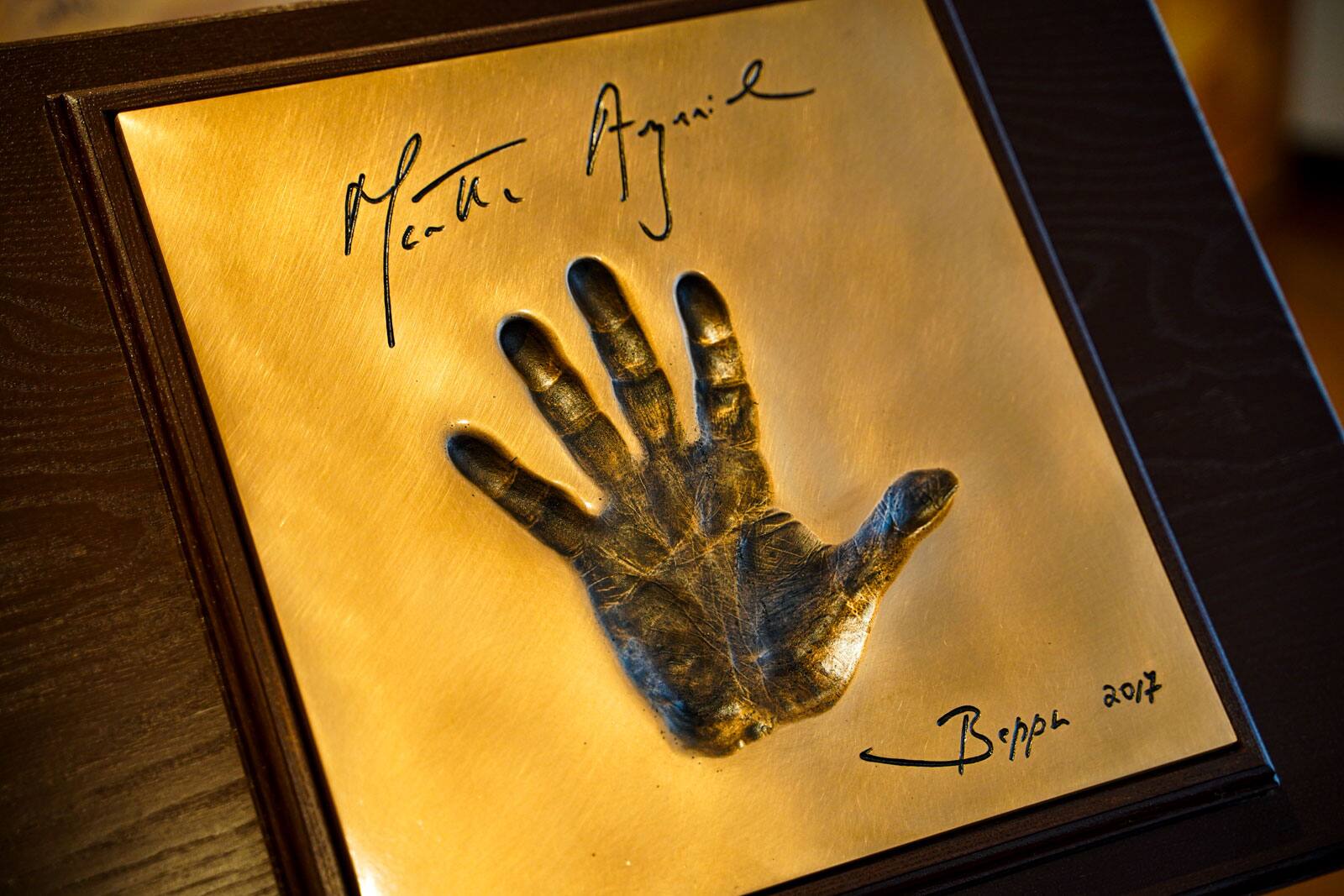 La huella de la mano de Martha Argerich fundida en latón sobre un panel de madera.