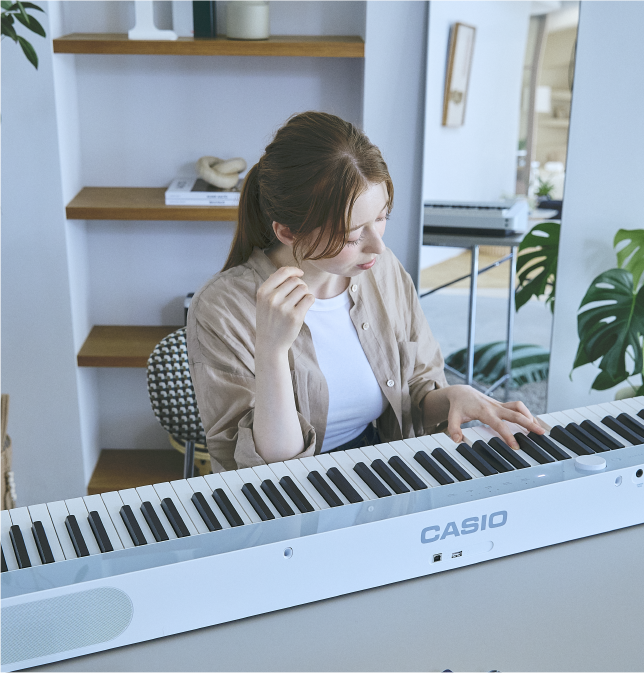 Una joven toca el piano digital Privia PX-S1100CB en color azul claro