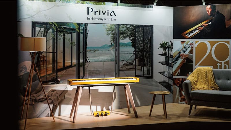 El Privia PX-S7000 amarillo mostaza en un pequeño escenario en el escaparate de EE.UU.
