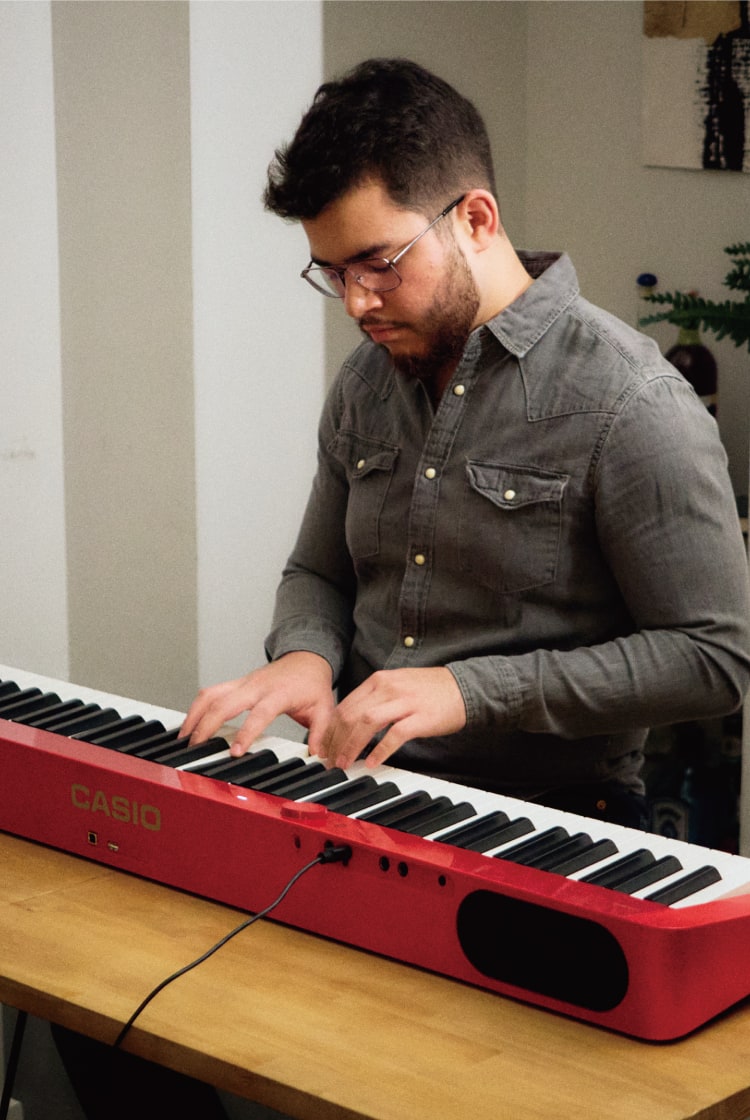 El pianista Oscar Rojas toca su piano Privia rojo en su apartamento de Boston. La imagen enlaza con su página Life with Privia.