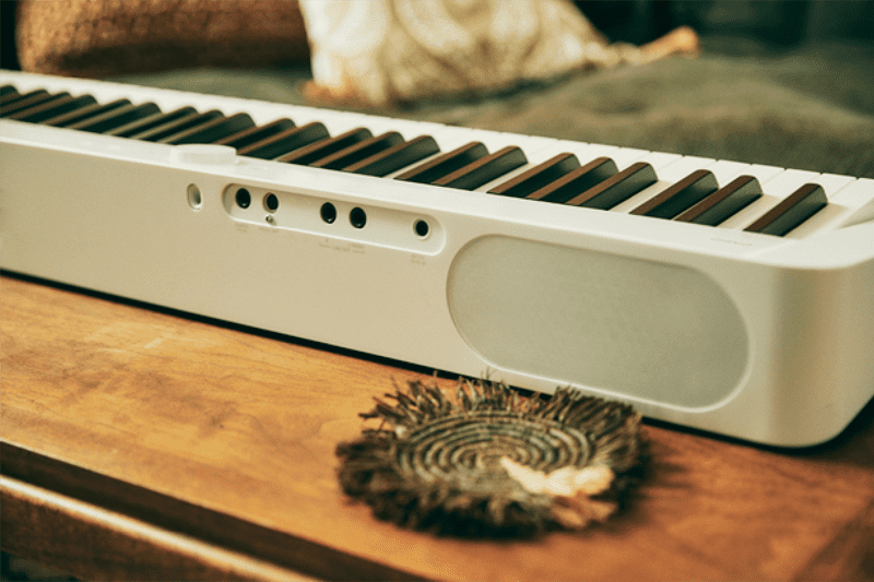 Primer plano de la parte trasera del piano digital Privia PX-S1100WE blanco con altavoces y conectores