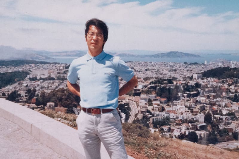 Hiroyuki Yoshino en los años 80 de pie sobre una colina con vistas a la ciudad