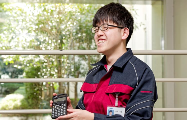 Yuma Matsumura, empleado del departamento de calidad, pelo negro y gafas, sostiene una calculadora gráfica CASIO en la mano.