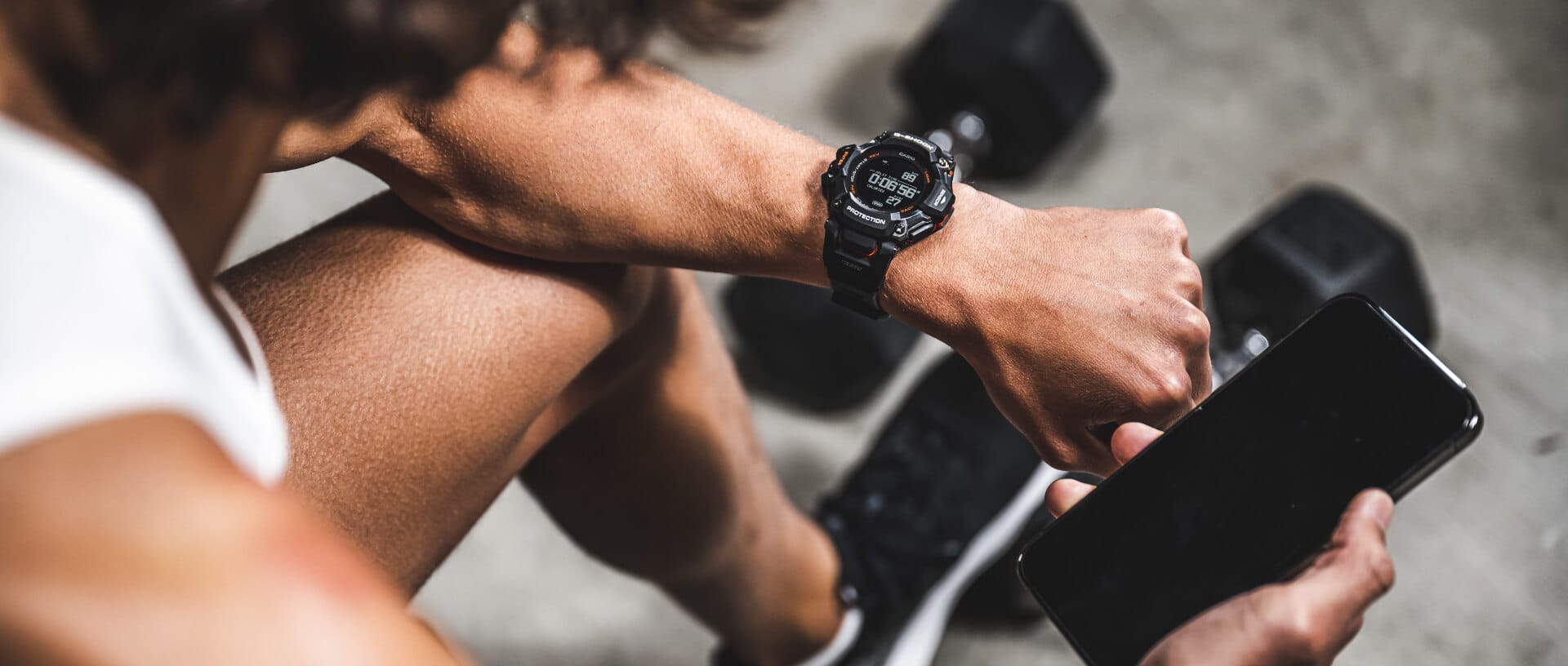 Vista aérea de un hombre que lleva el GBD-H200 y realiza un seguimiento de su entrenamiento en su smartphone.