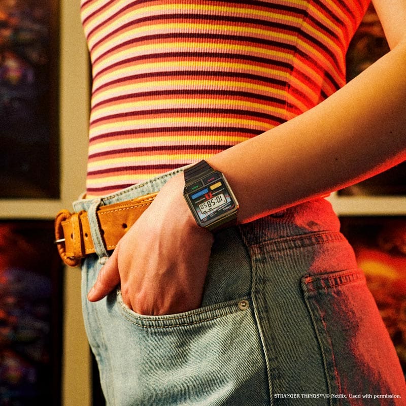 Una modelo lleva el Casio vintage "A120WEST-1A". En el fondo se puede ver una escena recreada de Stranger Things.